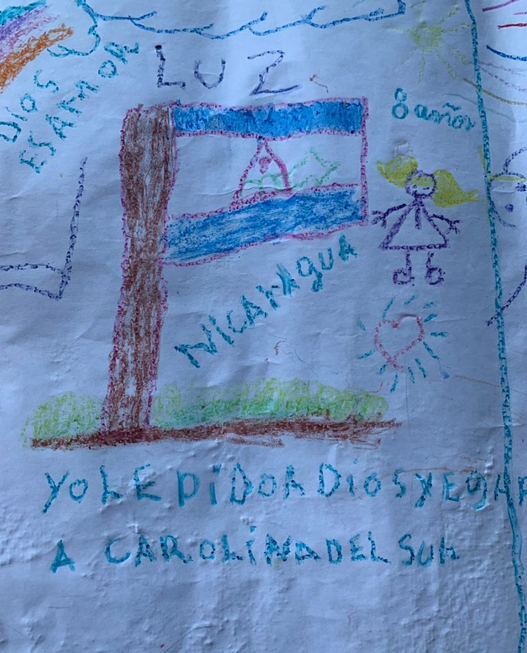 A girl writes "Yo le pido a Dios que llegamos a Carolina del Sur," or "I ask God that we can get to South Carolina." She is living in a tent encampment in Matamoros, across the border from Brownsville, Texas.